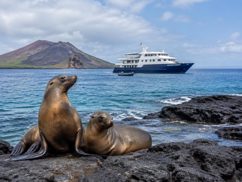 Small expedition yacht anchored near volcanic rocks