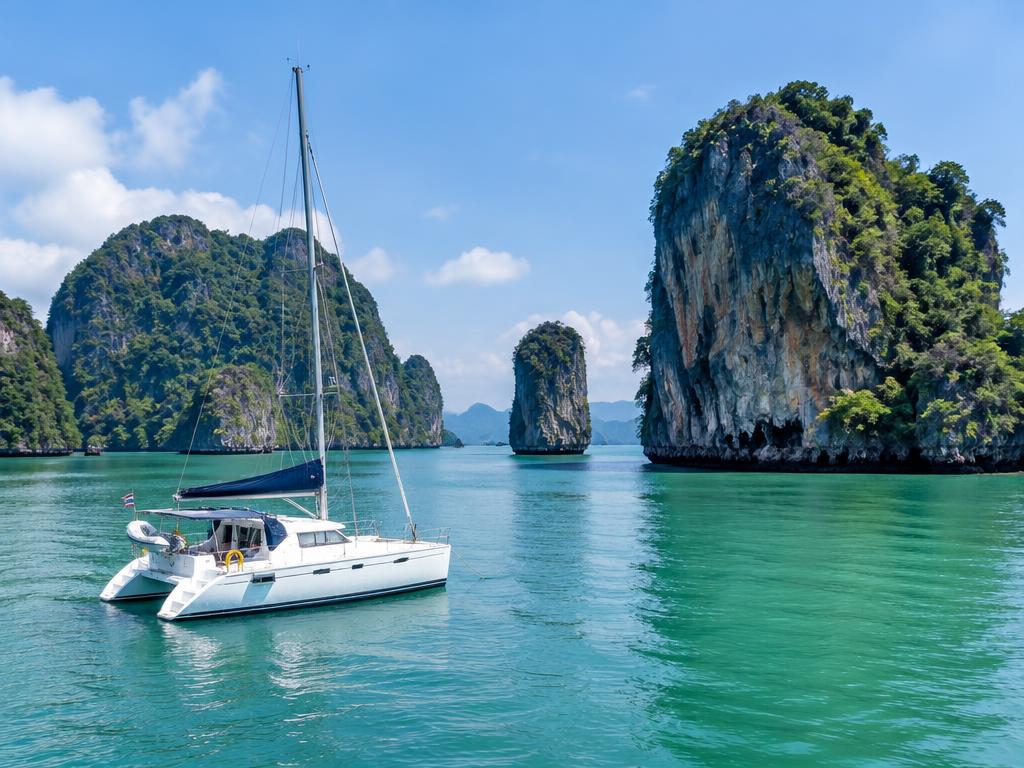Catamaran sailing among tall limestone islands